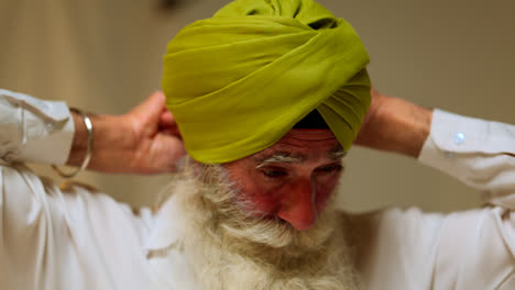 Studio-Shot-Of-Senior-Sikh-Man-With-Beard-Using-Salai-Needle-When-Putting-On-Turban-Against-Plain-Background-Shot-In-Real-Time-2